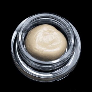 Hash rosin concentrate in a glass jar, showcasing a creamy, golden appearance.