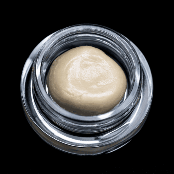 Hash rosin concentrate in a glass jar, showcasing a creamy, golden appearance.